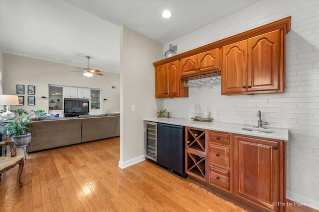 kitchen with light countertops, ceiling fan, a sink, light wood-type flooring, and fridge