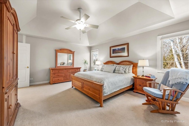 bedroom with light colored carpet, a tray ceiling, and multiple windows