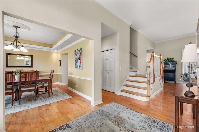 dining room with stairway, an inviting chandelier, ornamental molding, wood finished floors, and baseboards