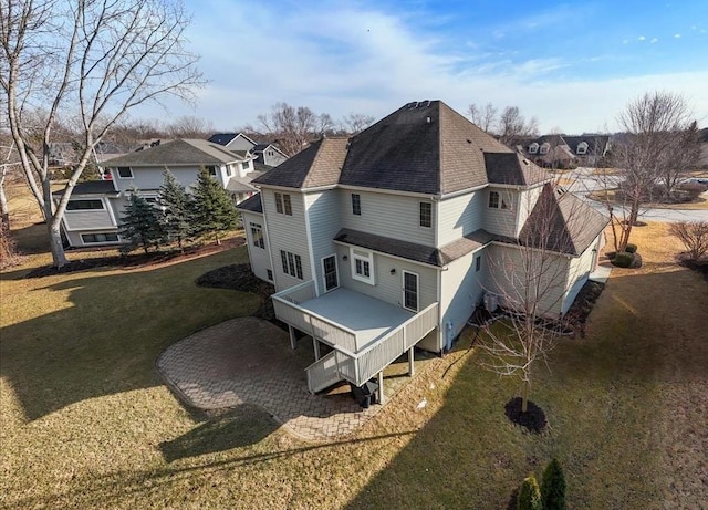 back of property featuring a shingled roof, a residential view, and a lawn