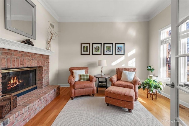 sitting room featuring baseboards, a fireplace, ornamental molding, and wood finished floors