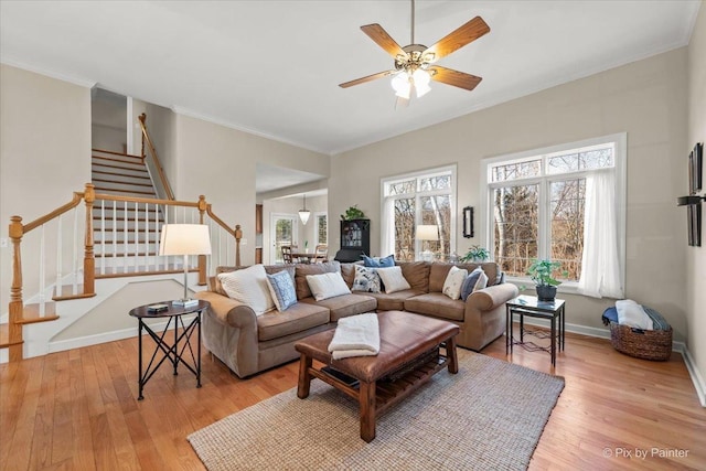 living area with ornamental molding, plenty of natural light, light wood finished floors, and stairs