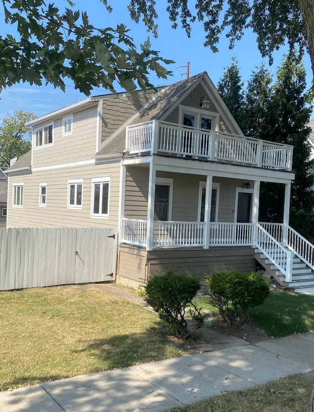 view of front facade featuring a porch, a front yard, fence, and a balcony