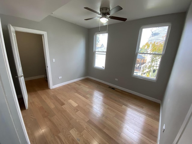 empty room featuring light wood-style floors, visible vents, baseboards, and a ceiling fan