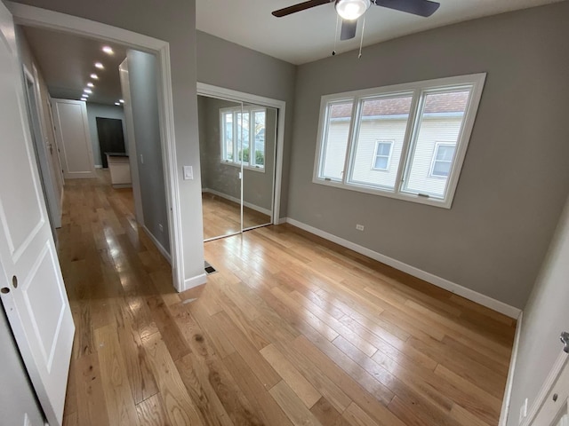 unfurnished bedroom with a ceiling fan, light wood-type flooring, a closet, and baseboards