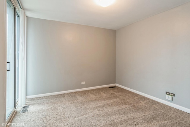 carpeted spare room featuring visible vents and baseboards