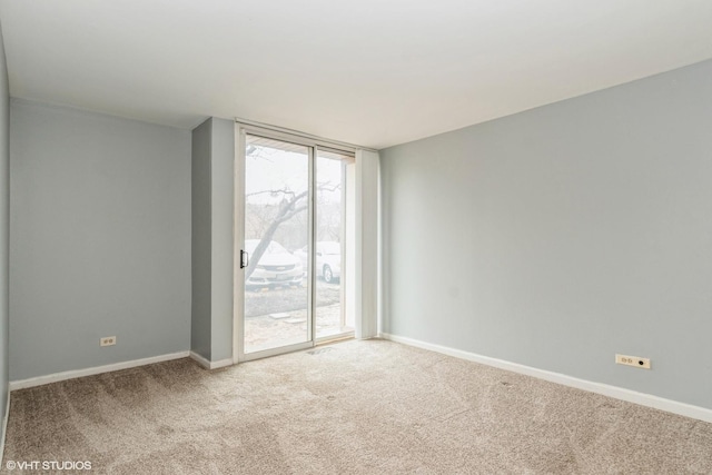 unfurnished room featuring a wall of windows, light carpet, and baseboards