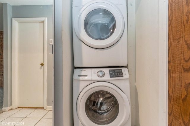 washroom with stacked washer / drying machine, laundry area, and light tile patterned flooring