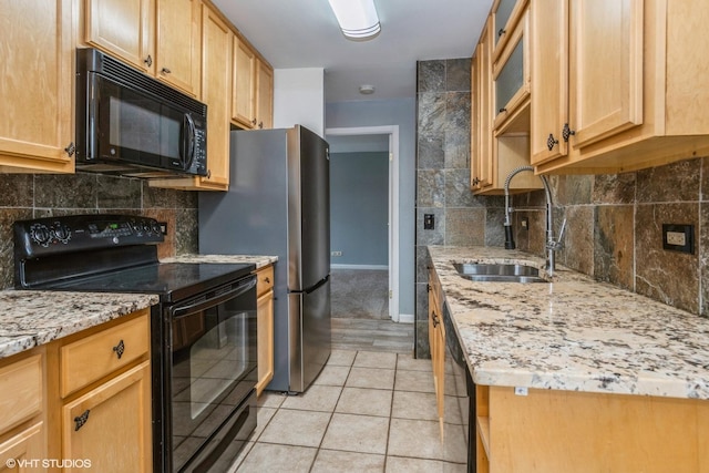 kitchen featuring light tile patterned floors, a sink, black appliances, light stone countertops, and baseboards