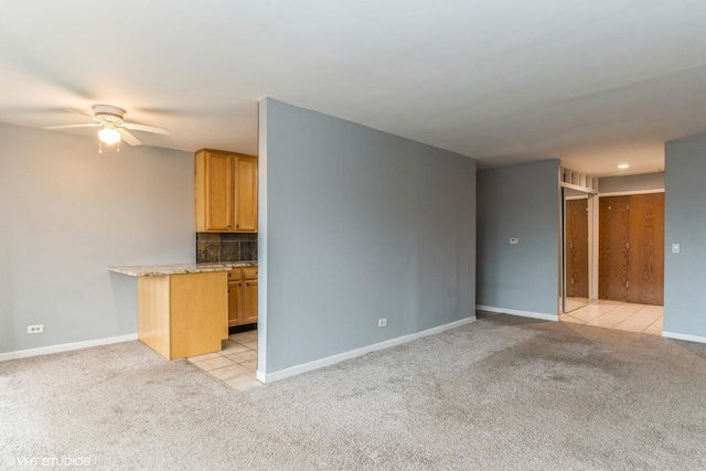 unfurnished living room with light carpet, ceiling fan, baseboards, and light tile patterned flooring