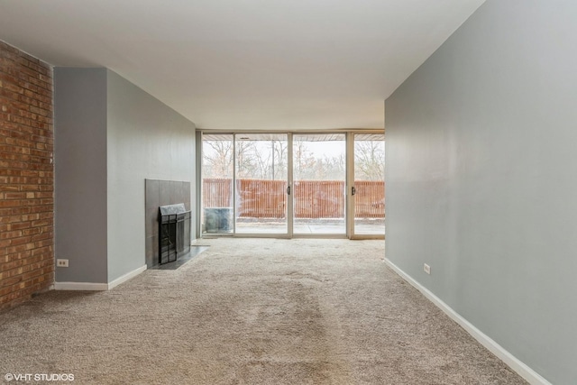 unfurnished living room featuring a wall of windows, carpet, a fireplace, and baseboards