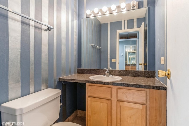 bathroom featuring vanity, toilet, and wallpapered walls