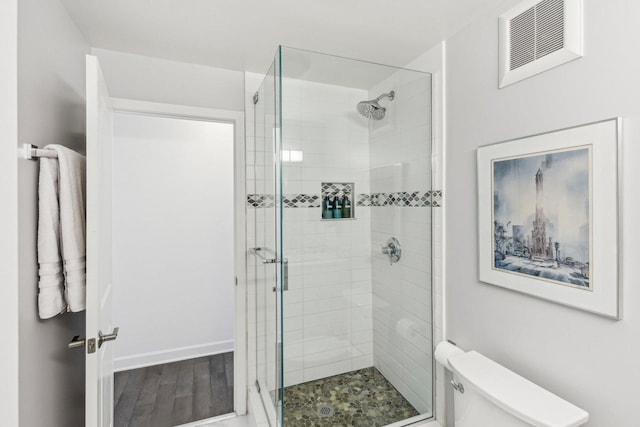 bathroom featuring toilet, a stall shower, visible vents, and wood finished floors