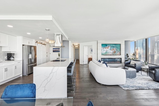 living area with dark wood-type flooring, a glass covered fireplace, and recessed lighting