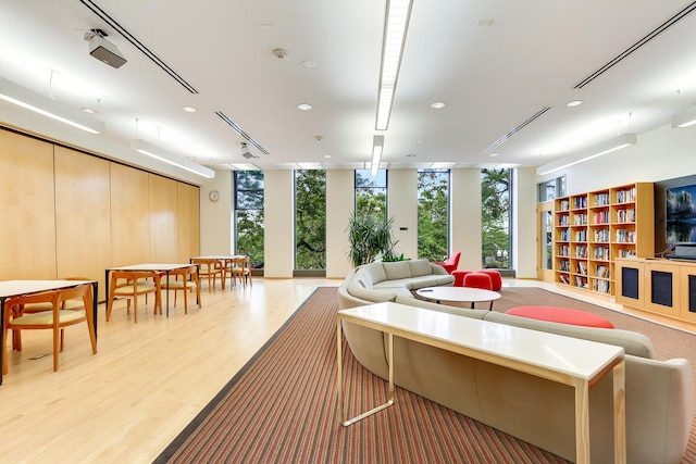 living room featuring a wall of windows, light wood-type flooring, and recessed lighting