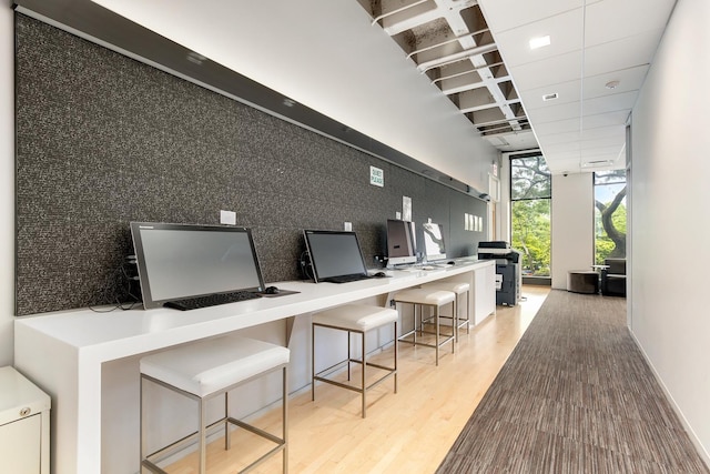 home office featuring visible vents, built in study area, wood finished floors, a wall of windows, and a drop ceiling