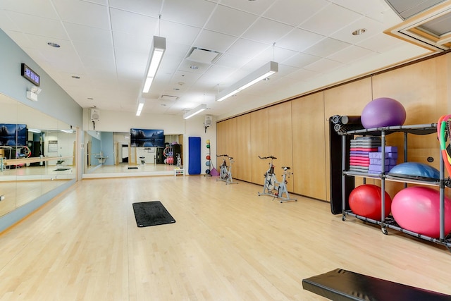 workout area with wood finished floors and a paneled ceiling