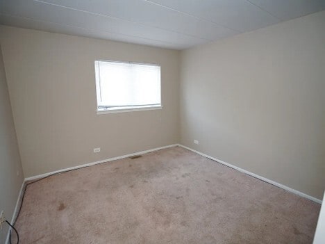 empty room featuring carpet and baseboards