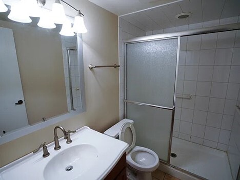 full bathroom featuring vanity, a shower stall, toilet, and tile patterned floors