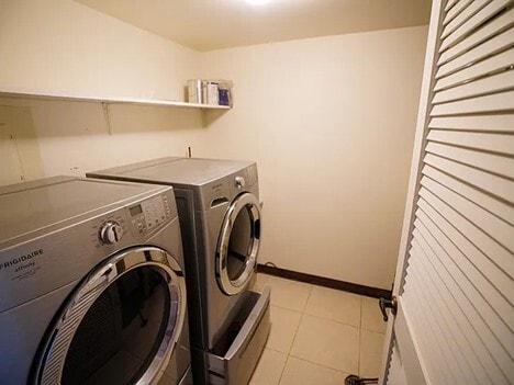 laundry area with laundry area, light tile patterned floors, baseboards, and separate washer and dryer