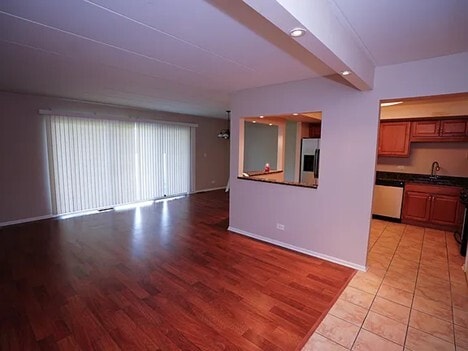 unfurnished living room with baseboards, a sink, and light wood finished floors