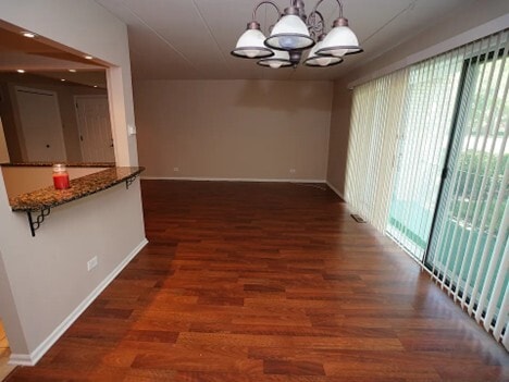 unfurnished dining area with baseboards, dark wood finished floors, and an inviting chandelier