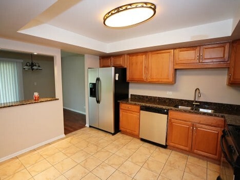 kitchen with range with electric cooktop, brown cabinetry, dishwasher, stainless steel refrigerator with ice dispenser, and a sink