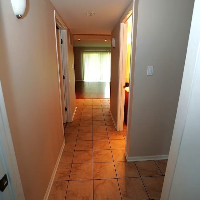 hallway with light tile patterned floors and baseboards