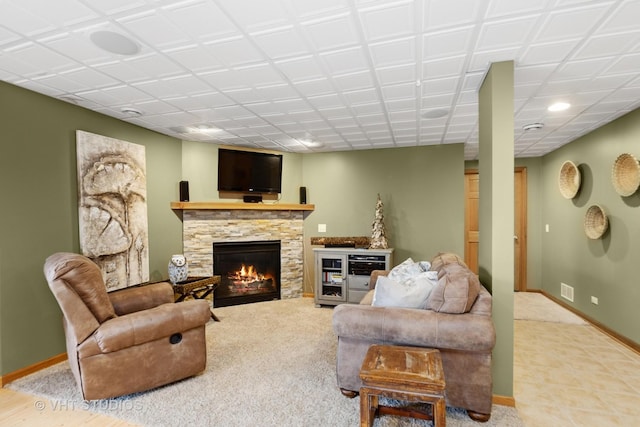 living room with visible vents, baseboards, and a stone fireplace