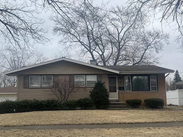 view of front of house featuring entry steps, brick siding, fence, and a garage