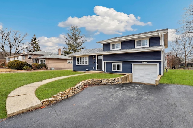 tri-level home featuring aphalt driveway, an attached garage, and a front lawn