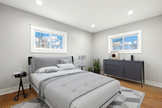 bedroom featuring recessed lighting, baseboards, multiple windows, and light wood-style floors