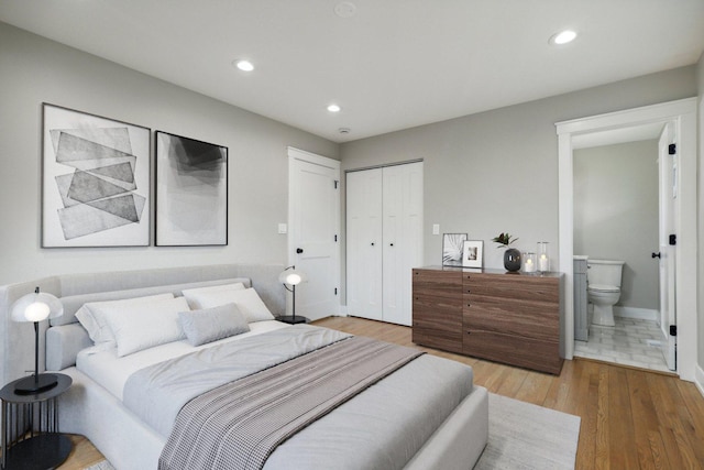 bedroom with ensuite bath, wood finished floors, recessed lighting, a closet, and baseboards