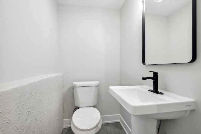 bathroom with toilet, baseboards, and a sink