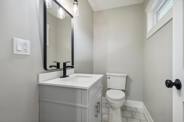 bathroom with vanity, toilet, and baseboards