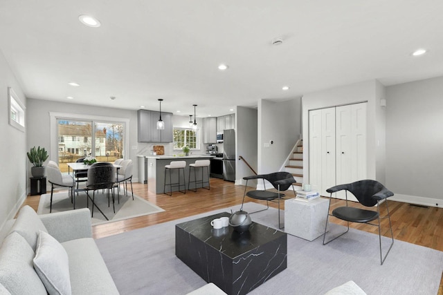 living area featuring stairway, recessed lighting, light wood-style flooring, and baseboards