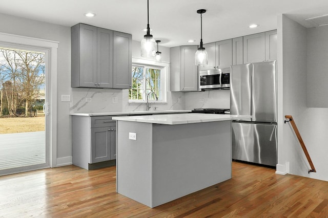 kitchen featuring a kitchen island, gray cabinets, stainless steel appliances, and light wood-style flooring