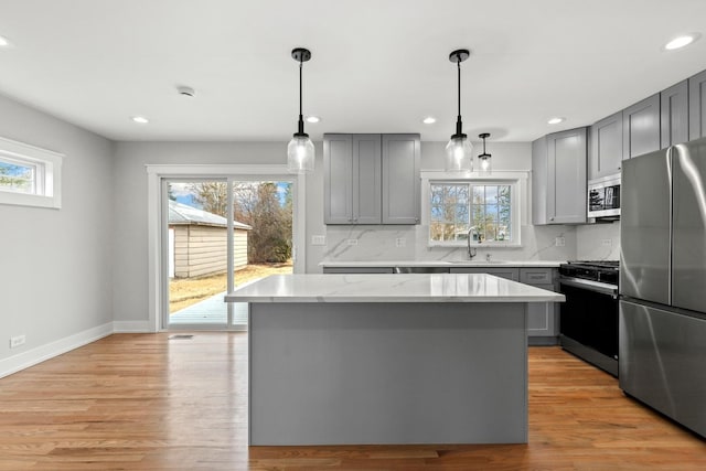 kitchen with tasteful backsplash, gray cabinetry, a center island, appliances with stainless steel finishes, and a sink