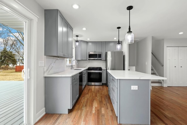 kitchen featuring light wood finished floors, gray cabinets, appliances with stainless steel finishes, and a sink