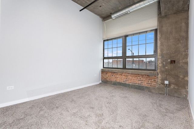 carpeted spare room featuring a towering ceiling and baseboards