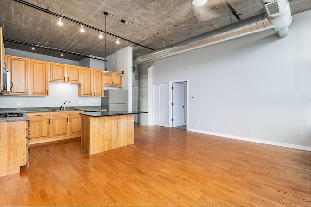 kitchen with a center island, light wood finished floors, a towering ceiling, freestanding refrigerator, and light brown cabinets