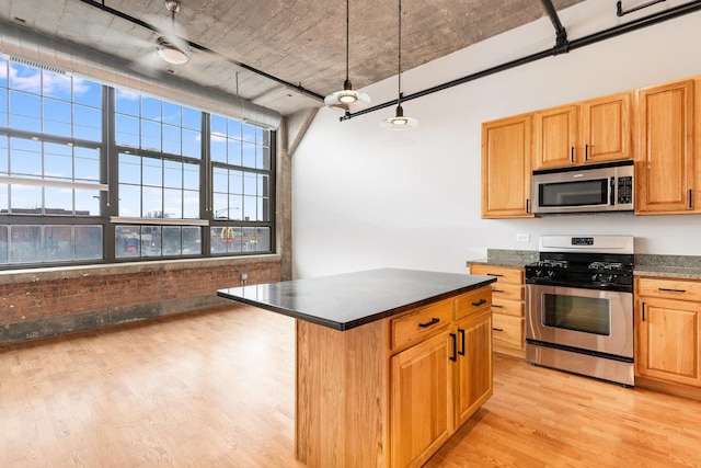 kitchen featuring stainless steel appliances, dark countertops, a center island, and light wood-style flooring