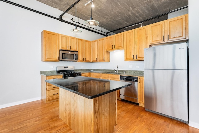 kitchen featuring light wood-style floors, stainless steel appliances, a sink, and light brown cabinetry