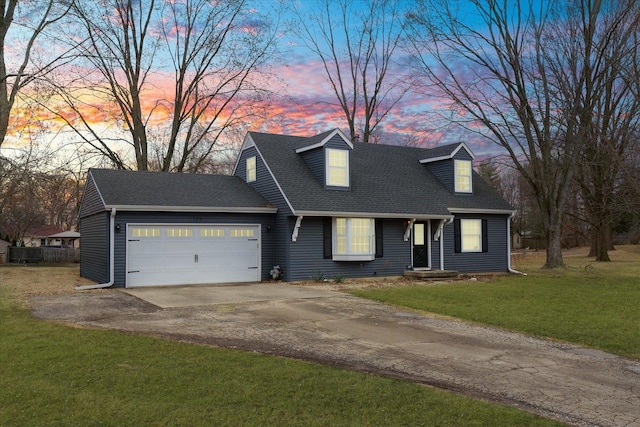 cape cod home featuring a yard, a garage, driveway, and a shingled roof