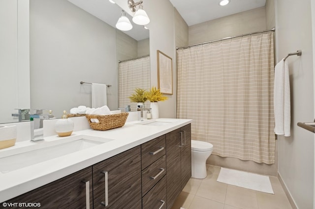 bathroom featuring tile patterned floors, double vanity, toilet, and a sink