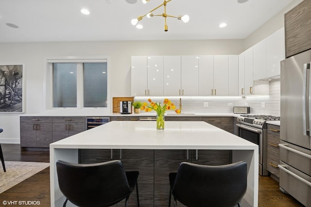 kitchen featuring a kitchen island, stainless steel appliances, wine cooler, a kitchen bar, and modern cabinets