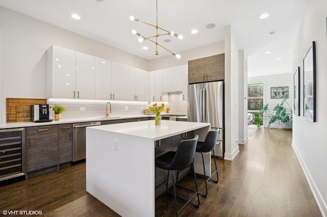 kitchen featuring a sink, a kitchen breakfast bar, a kitchen island, wine cooler, and appliances with stainless steel finishes