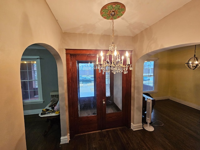 foyer entrance with a chandelier, a healthy amount of sunlight, baseboards, and wood finished floors