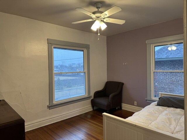 bedroom featuring ceiling fan, multiple windows, baseboards, and dark wood finished floors