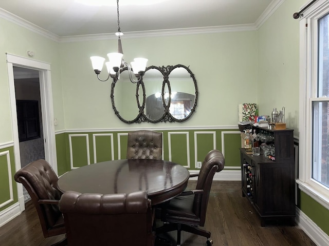 dining space with an inviting chandelier, crown molding, a decorative wall, and wood finished floors